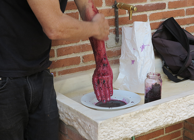 L'artista Sulé Duc tenyint-se el braç amb pigment de 