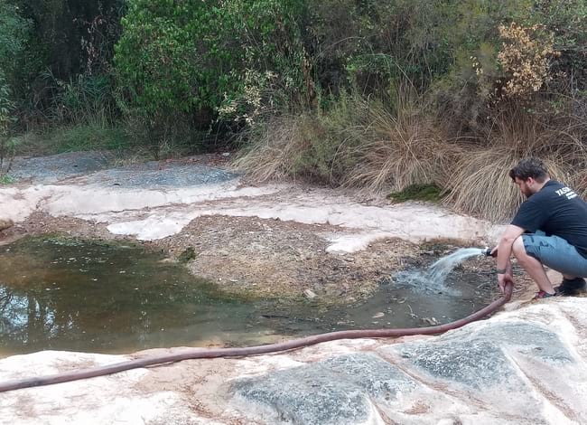 Un dels voluntaris de la SCCP omplint amb aigua de pou una de les basses. Autor: SCCP