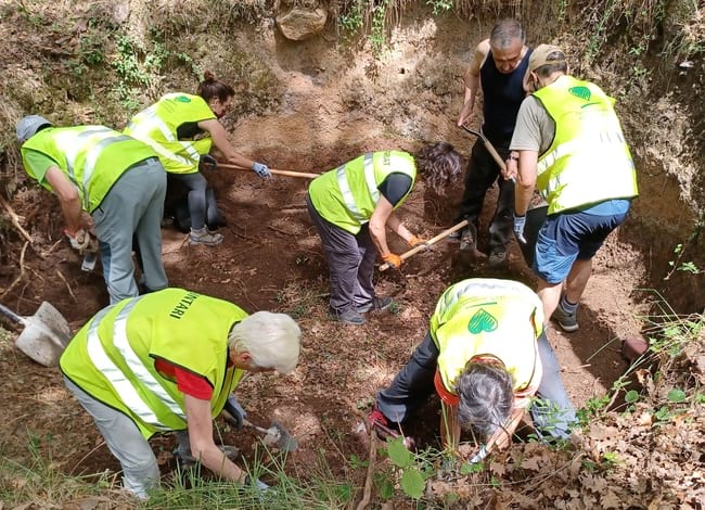 Grup de voluntaris buidant de terra, arrels i altres restes un antic forn de calç. Autor: Cercle de Voluntaris